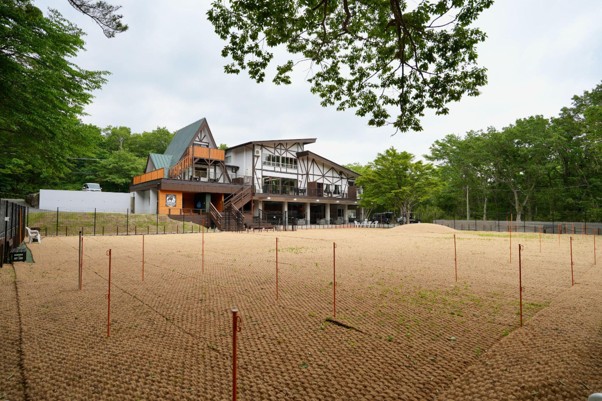 施設の建物とココペーバーを敷いたドッグラン