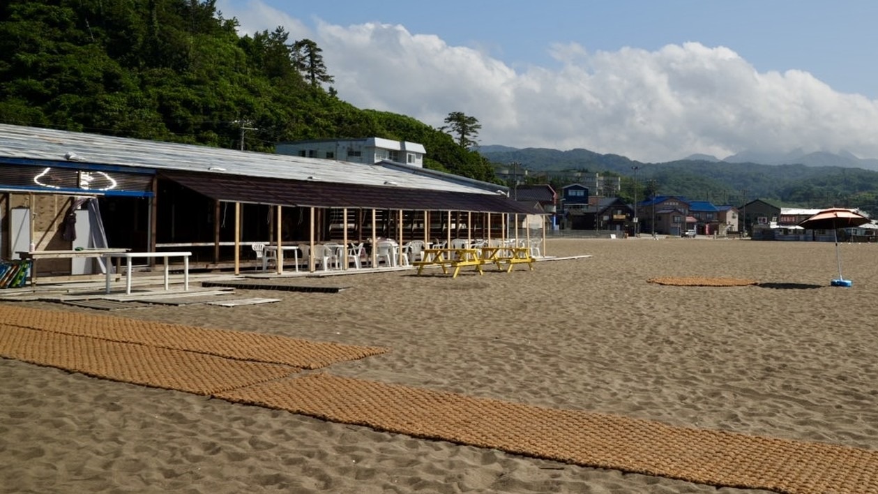 鯨波海水浴場の砂浜に敷かれたココペーバーと海の家タローズビーチの全景