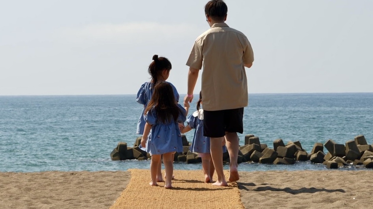 ココペーバーの通路を歩いて海へ向かう家族